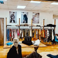 A clothing store with racks of clothes, folded garments and a mannequin. Fashion photos hang on the wall., &copy; StuttgARTfactory