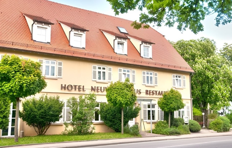 A hotel with a red roof and several windows, surrounded by green trees and shrubs, situated on a street., © Hotel Neuwirtshaus A hotel with a red roof and several windows, surrounded by green trees and shrubs, situated on a street., © Hotel Neuwirtshaus