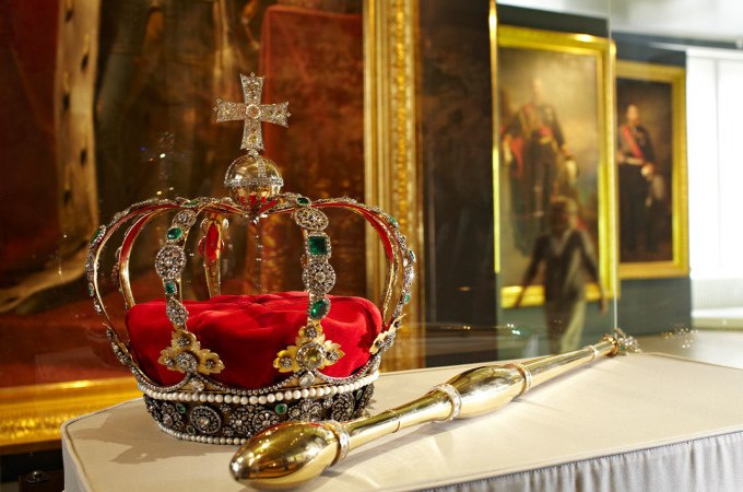 Eine reich verzierte Krone und ein Zepter auf einem Podest in einem Museum, umgeben von Gem&auml;lden., &copy; Landesmuseum W&uuml;rttemberg
