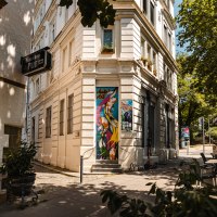 Eine Straßenecke mit einem Pub-Schild, bunter Wandkunst und Café-Tischen unter einem Sonnenschirm., © SMG Stuttgart Marketing GmbH - Sarah Schmid Eine Straßenecke mit einem Pub-Schild, bunter Wandkunst und Café-Tischen unter einem Sonnenschirm., © SMG Stuttgart Marketing GmbH - Sarah Schmid