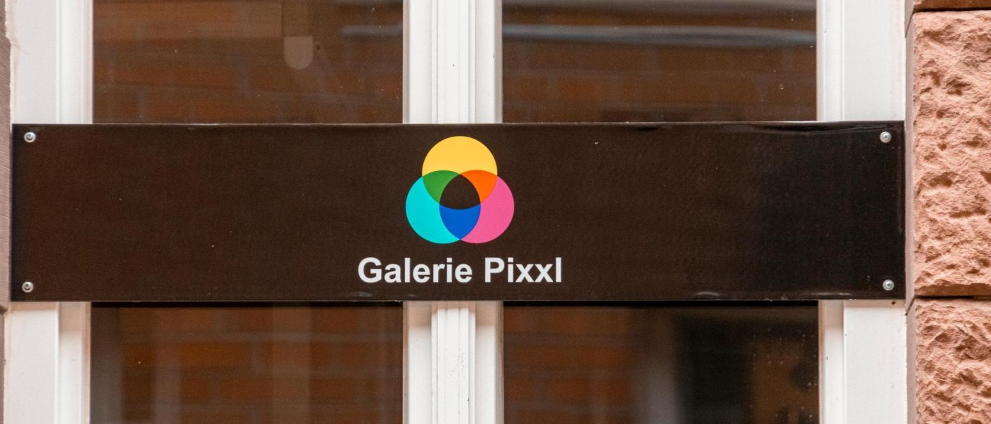 Ein Schild der Galerie Pixxl mit einem bunten, überlappenden Kreis-Logo auf schwarzem Hintergrund., © Stuttgart-Marketing GmbH, Sarah Schmid Ein Schild der Galerie Pixxl mit einem bunten, überlappenden Kreis-Logo auf schwarzem Hintergrund., © Stuttgart-Marketing GmbH, Sarah Schmid