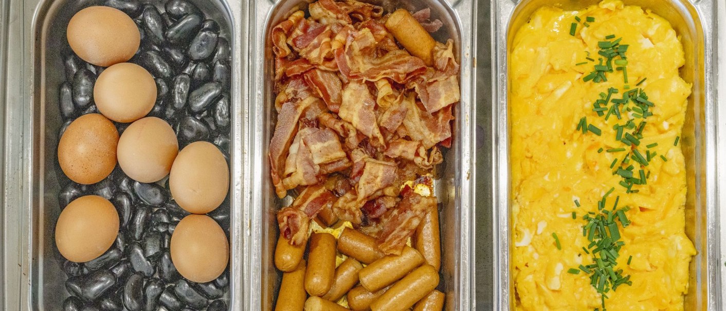 Three containers with breakfast ingredients: Eggs on stones, bacon and sausages, scrambled eggs with chives., © Plaza INN Stuttgart-Filderstadt Three containers with breakfast ingredients: Eggs on stones, bacon and sausages, scrambled eggs with chives., © Plaza INN Stuttgart-Filderstadt