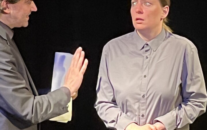 Zwei Personen in einem Theaterst&uuml;ck. Eine Person spricht gestikulierend, die andere schaut ernst. Dunkler Hintergrund., &copy; Theater Atelier