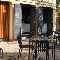 Outdoor area of the 1819 Bistro am Wirtemberg with black tables and chairs on paved ground, surrounded by green vegetation., © 1819 Bistro am Wirtemberg
