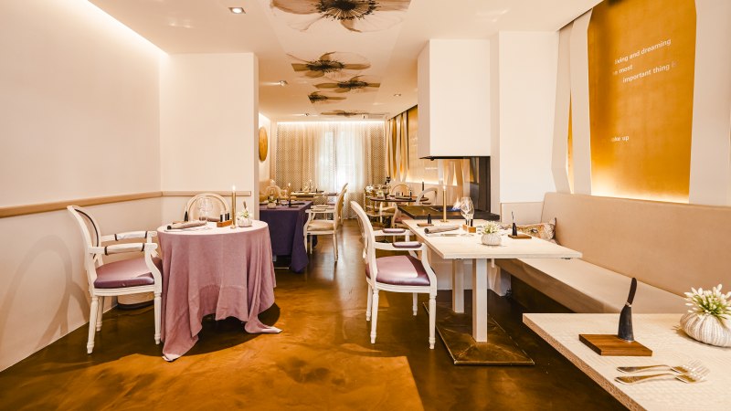 Elegantes Restaurant mit stilvoller Dekoration, gedeckten Tischen und warmem Licht. Blumenmuster an der Decke und moderne Einrichtung schaffen eine einladende Atmosphäre., © Zauberlehrling Elegantes Restaurant mit stilvoller Dekoration, gedeckten Tischen und warmem Licht. Blumenmuster an der Decke und moderne Einrichtung schaffen eine einladende Atmosphäre., © Zauberlehrling
