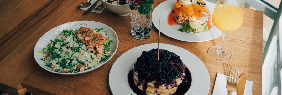 A table with salad, pancakes with berries, a drink and other dishes on a wooden table., &copy; The Gardeners Nosh, Stuttgart