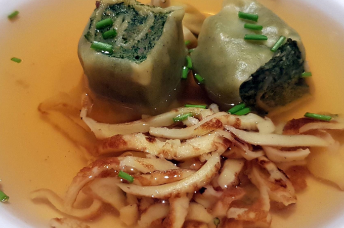 Zwei Maultaschen in klarer Br&uuml;he, garniert mit Schnittlauch und Pfannkuchenstreifen, serviert in einer wei&szlig;en Sch&uuml;ssel., &copy; Kultweine-Kochwelten-Kunst&uuml;cke - Kochschule Sonja Lenz