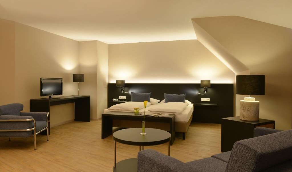 Modern double room with double bed, sofa, TV and stylish lighting. Subtle colors and elegant design create a cozy atmosphere., &copy; relexa Waldhotel Schatten