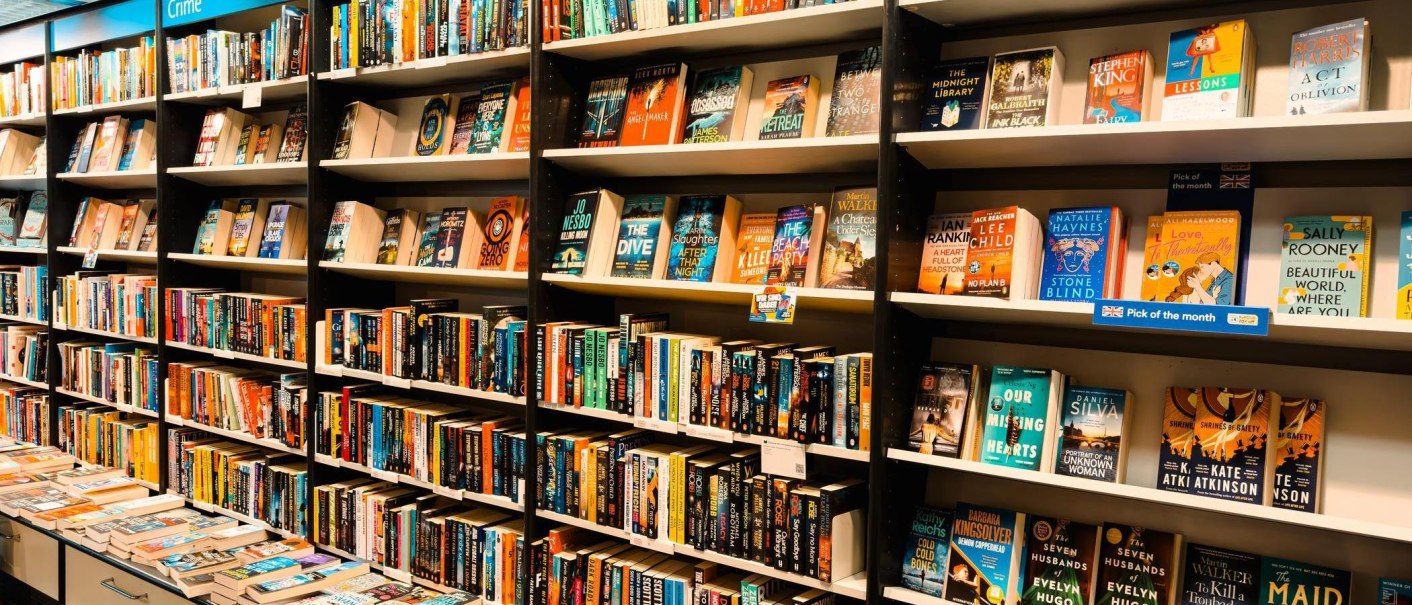 Ein Bücherregal in einer Buchhandlung, gefüllt mit englischsprachigen Büchern. Oben steht "Crime". Verschiedene Genres und Titel sind sichtbar., © Wittwer -Thalia / Schiek Media