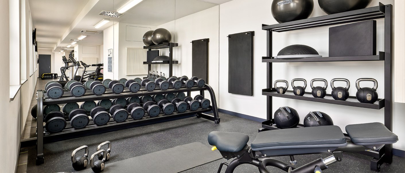Ein gut ausgestatteter Fitnessraum mit Hanteln, Kettlebells, Gymnastikb&auml;llen und Trainingsb&auml;nken vor einem gro&szlig;en Spiegel., &copy; Aloft Stuttgart