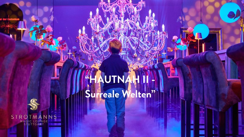 Ein Junge steht in einer surrealen, farbenfrohen Umgebung mit Kronleuchter und Nebel. Schriftzug: "HAUTNAH II - Surreale Welten". Strotmanns Magic Lounge Stuttgart., &copy; Strotmanns Magic Lounge