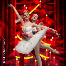 Zwei Balletttänzer in Nussknacker-Kostümen posieren vor einem leuchtend roten Hintergrund. Die Tänzerin trägt ein weißes Tutu., © links im Bild Zwei Balletttänzer in Nussknacker-Kostümen posieren vor einem leuchtend roten Hintergrund. Die Tänzerin trägt ein weißes Tutu., © links im Bild