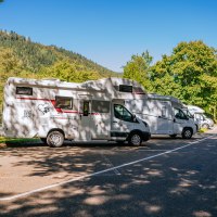 Wohnmobilstellplatz in Bad Wildbad mit mehreren Wohnmobilen, umgeben von Bäumen und Bergen bei sonnigem Wetter., © Stuttgart-Marketing GmbH, Thomas Niedermüller