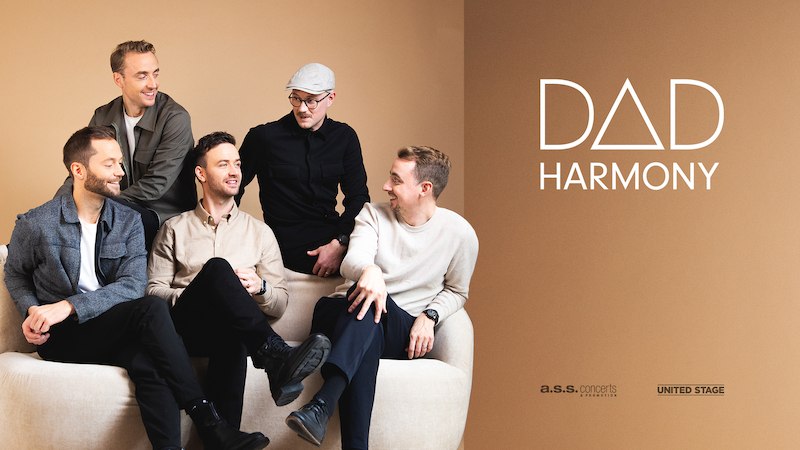 Fünf Männer sitzen lächelnd auf einem Sofa vor einem beigen Hintergrund. Der Schriftzug 'Dad Harmony' ist rechts im Bild zu sehen., © C2 Concerts GmbH Fünf Männer sitzen lächelnd auf einem Sofa vor einem beigen Hintergrund. Der Schriftzug 'Dad Harmony' ist rechts im Bild zu sehen., © C2 Concerts GmbH