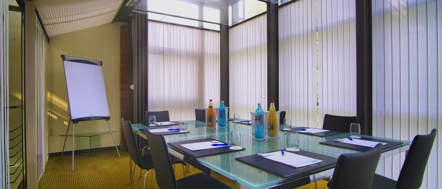 Modern meeting room with glass table, chairs, flipchart and drinks. Bright blinds let in light., &copy; TOMAS