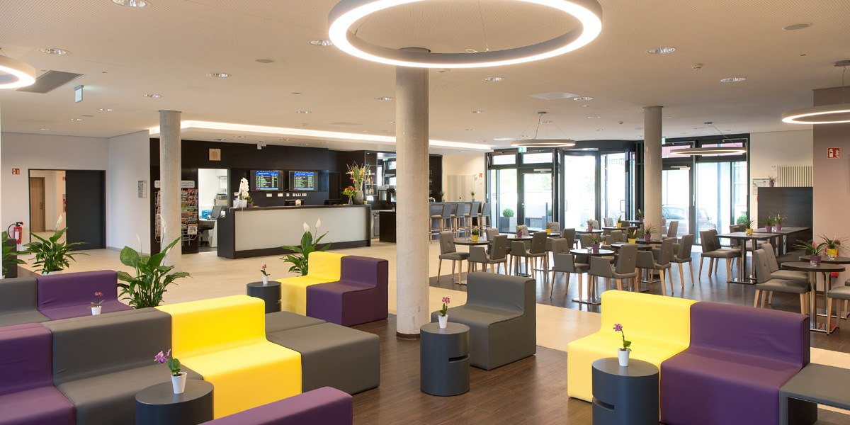 Moderne Lobby mit bunten Sitzmöbeln, Tischen und Pflanzen. Helle Beleuchtung und große Fenster sorgen für eine einladende Atmosphäre., © Star Inn Stuttgart Airport-Messe Moderne Lobby mit bunten Sitzmöbeln, Tischen und Pflanzen. Helle Beleuchtung und große Fenster sorgen für eine einladende Atmosphäre., © Star Inn Stuttgart Airport-Messe