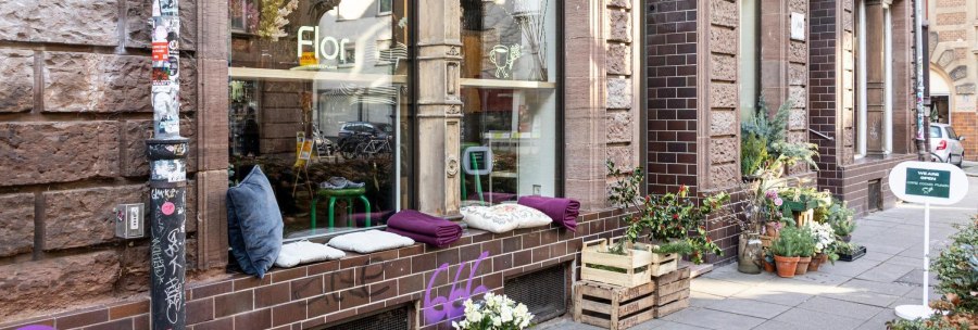 A cozy caf&eacute; with plants and cushions on the windowsill. A sign advertises coffee and cookies. The fa&ccedil;ade is made of brown bricks., &copy; Stuttgart-Marketing GmbH, Sarah Schmid