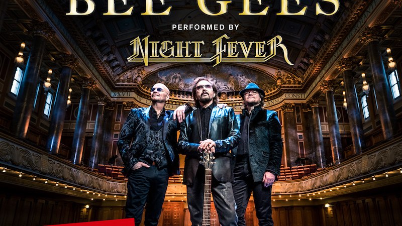 Drei Männer in einem eleganten Konzertsaal, einer hält eine blaue Gitarre. Text: 'A Tribute to the Bee Gees', 'Tournee 2025'. Prächtige Architektur im Hintergrund., © Music Circus Concertbüro GmbH & Co. KG