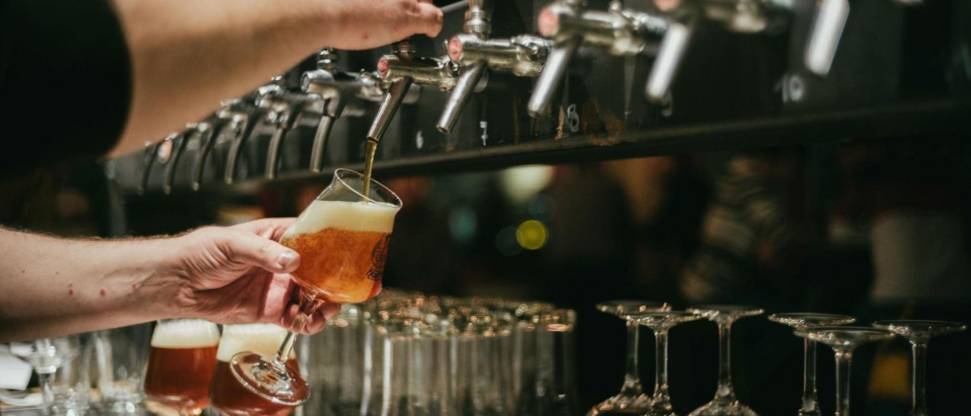 A glass of beer is being filled at a tap. Other glasses and taps can be seen in the background., © Kraftpaule A glass of beer is being filled at a tap. Other glasses and taps can be seen in the background., © Kraftpaule