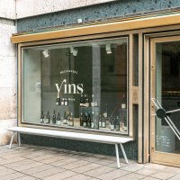 Schaufenster des Weinhandels 'Vins Gute Weine' mit Weinflaschen im Display und einer Bank davor., © SMG, Sarah Schmid Schaufenster des Weinhandels 'Vins Gute Weine' mit Weinflaschen im Display und einer Bank davor., © SMG, Sarah Schmid