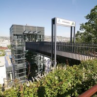 Moderne Jugendherberge in Stuttgart mit Glasfassade und Br&uuml;cke, umgeben von gr&uuml;ner Vegetation und Stadtblick im Hintergrund., &copy; TOMAS