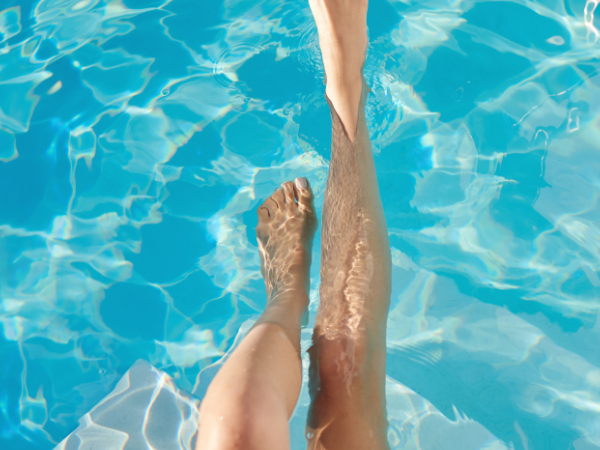 Zwei Beine tauchen in das klare, blaue Wasser eines Pools ein. Die Sonne reflektiert auf der Wasseroberfl&auml;che und erzeugt ein Spiel aus Licht und Schatten., &copy; Stadtwerke Ludwigsburg-Kornwestheim GmbH