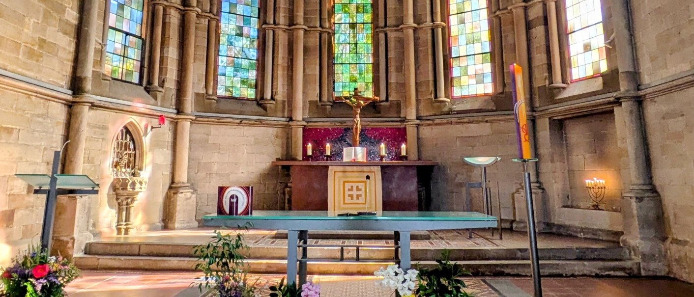 Kirchenaltar im Chorraum mit Kruzifix, Kerzen und farbigen Glasfenstern in einer gotischen Kirche., © St. Katharina Stuttgart Kirchenaltar im Chorraum mit Kruzifix, Kerzen und farbigen Glasfenstern in einer gotischen Kirche., © St. Katharina Stuttgart