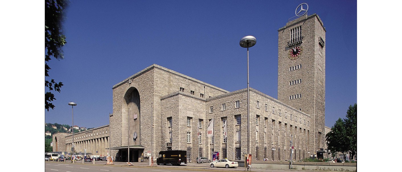 Stuttgart Central Station, with its striking clock tower and Mercedes star, surrounded by cars and trees, under a clear blue sky., &copy; Stuttgart-Marketing GmbH