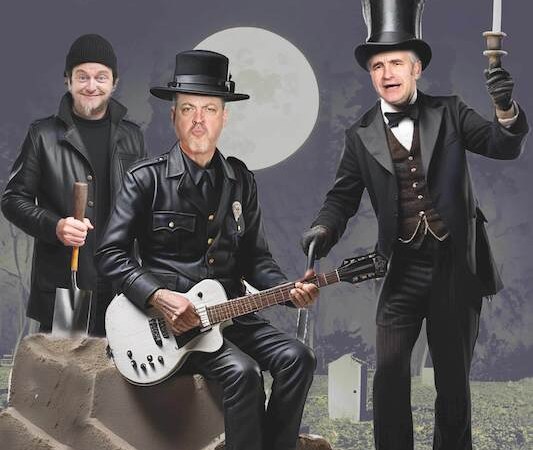 Drei Männer in verschiedenen Kostümen stehen auf einem Friedhof. Einer hält eine Gitarre, ein anderer eine Kerze. Der Vollmond leuchtet im Hintergrund., © Theaterhaus Stuttgart e.V.