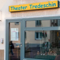 Eingang des Theater Tredeschin mit einem gelben Schild über der Tür. Ein Fenster mit Vorhang und ein kleiner Schaukasten sind sichtbar., © SMG, Sarah Schmid Eingang des Theater Tredeschin mit einem gelben Schild über der Tür. Ein Fenster mit Vorhang und ein kleiner Schaukasten sind sichtbar., © SMG, Sarah Schmid
