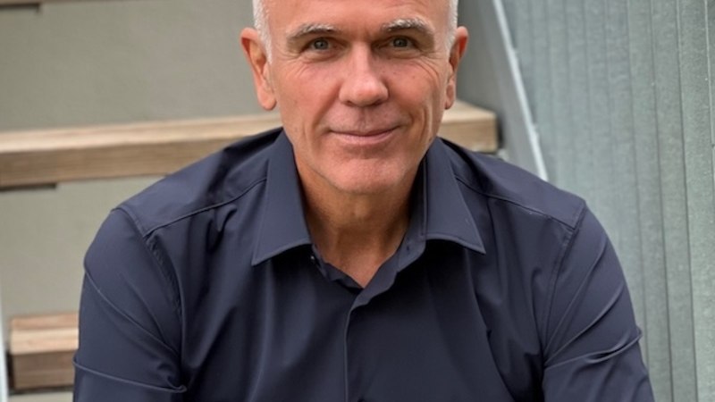 Ein Mann mit grauem Haar und dunklem Hemd sitzt auf einer Treppe und lächelt in die Kamera., © Renitenztheater Stuttgart e.V. Ein Mann mit grauem Haar und dunklem Hemd sitzt auf einer Treppe und lächelt in die Kamera., © Renitenztheater Stuttgart e.V.