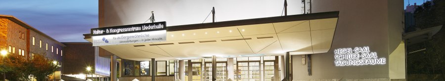 Eingang der Liederhalle Stuttgart bei D&auml;mmerung, beleuchtet mit Schildern f&uuml;r Hegel-Saal, Schiller-Saal und Tagungsr&auml;ume., &copy; Kultur- und Kongresszentrum Liederhalle