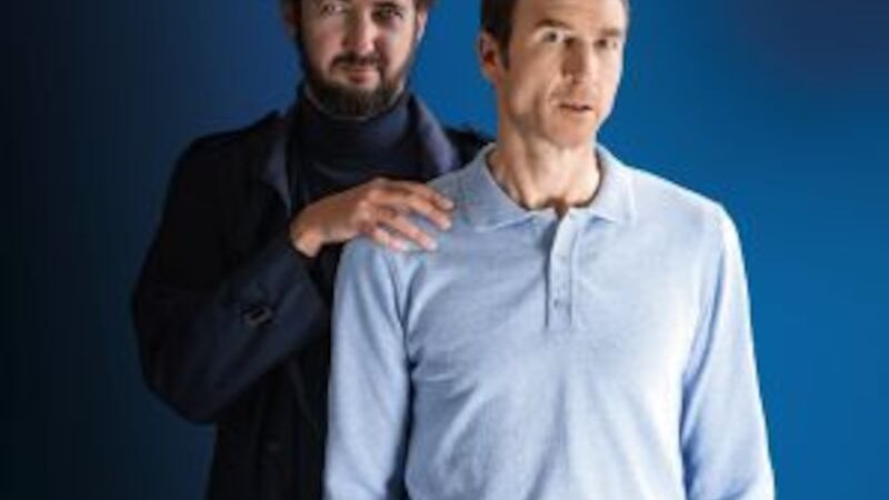 Zwei Männer stehen vor einem blauen Hintergrund. Der vordere trägt ein hellblaues Hemd, der hintere dunkle Kleidung und legt die Hände auf die Schultern des vorderen., © Altes Schauspielhaus und Komödie im Marquardt e.V. Zwei Männer stehen vor einem blauen Hintergrund. Der vordere trägt ein hellblaues Hemd, der hintere dunkle Kleidung und legt die Hände auf die Schultern des vorderen., © Altes Schauspielhaus und Komödie im Marquardt e.V.