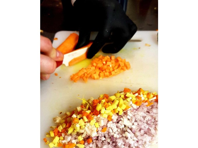 One person cuts carrots into small cubes on a chopping board. Other diced ingredients are already prepared., © Kultweine-Kochwelten-Kunstücke - Kochschule Sonja Lenz One person cuts carrots into small cubes on a chopping board. Other diced ingredients are already prepared., © Kultweine-Kochwelten-Kunstücke - Kochschule Sonja Lenz