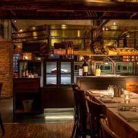 Stylish restaurant with brick walls, laid tables and bottles of wine. Warm light creates a cozy atmosphere., &copy; &copy;Pier 51