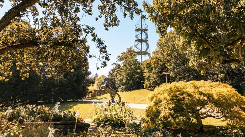A green park with trees, a horse sculpture and a spiral-shaped observation tower in the background., &copy; SMG Stuttgart Marketing GmbH - Sarah Schmid