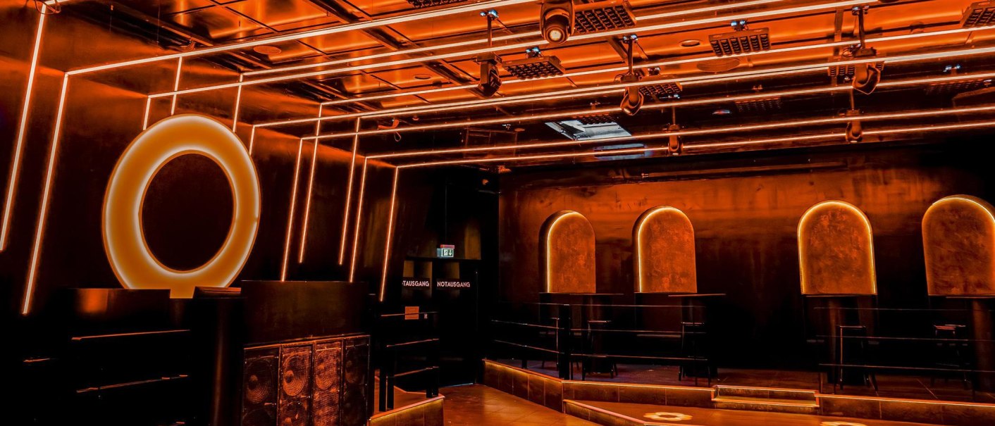 Ein moderner Clubraum mit orangefarbener Beleuchtung, geometrischen Formen und stilvollen Designelementen. Der Raum wirkt futuristisch und einladend., © Wonders, Stuttgart