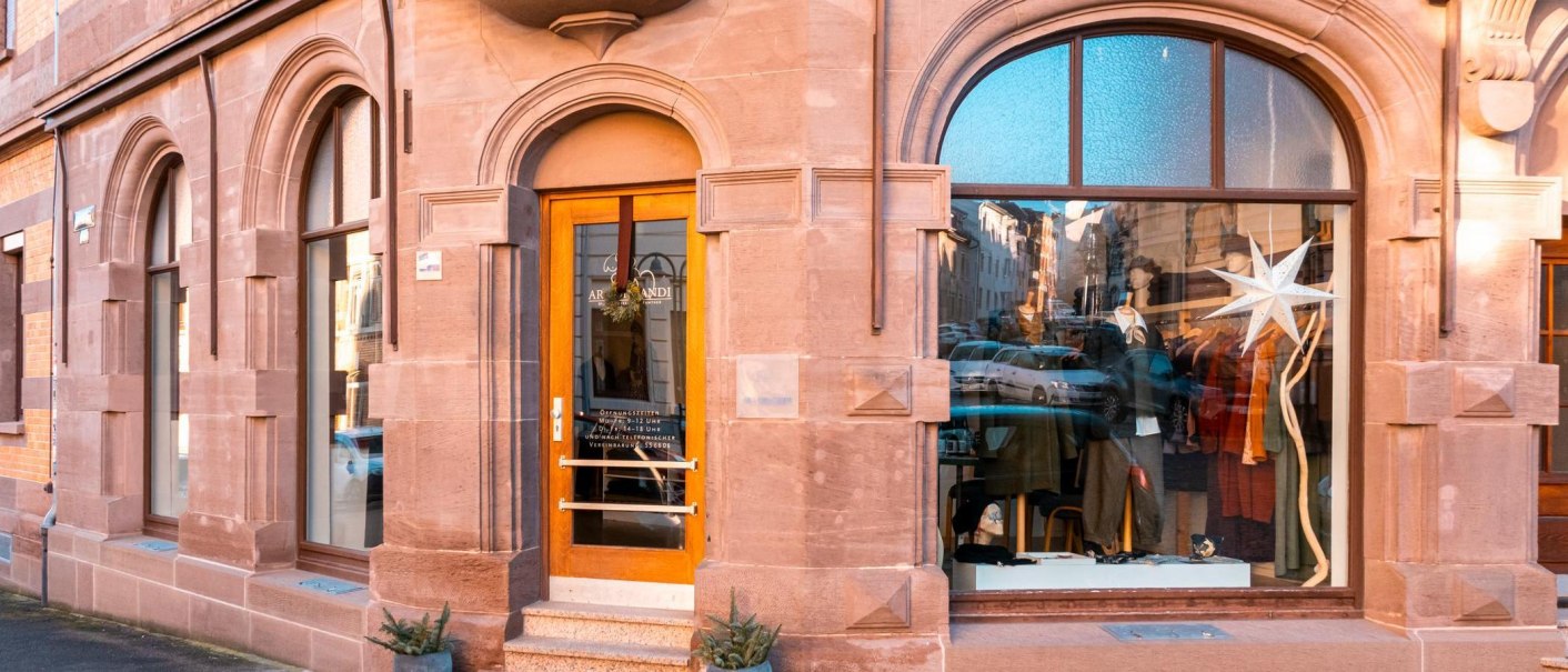 Eingang eines Modegesch&auml;fts mit gro&szlig;en Fenstern und dekorativem Stern. Die Fassade ist aus rotem Sandstein., &copy; SMG, Sarah Schmid
