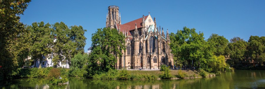 Die Johanneskirche am Feuersee in Stuttgart, umgeben von B&auml;umen und reflektiert im Wasser, bei klarem, sonnigem Wetter., &copy; SMG Achim Mende