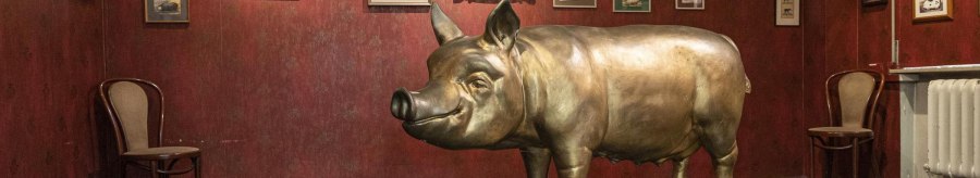 A room in the Stuttgart Pig Museum with a large pig sculpture and numerous framed pictures on a red wall., © Stuttgart-Marketing GmbH, Sarah Schmid