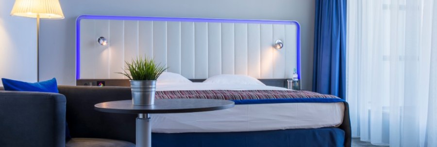 Modern guest room with double bed, blue lighting, table with plant, sofa and floor lamp., © Park Inn by Radisson Stuttgart Modern guest room with double bed, blue lighting, table with plant, sofa and floor lamp., © Park Inn by Radisson Stuttgart