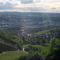 Panoramablick auf Untertürkheim: Weinberge im Vordergrund, Stadt und Industriegebäude im Hintergrund unter bewölktem Himmel., © Stuttgart-Marketing GmbH