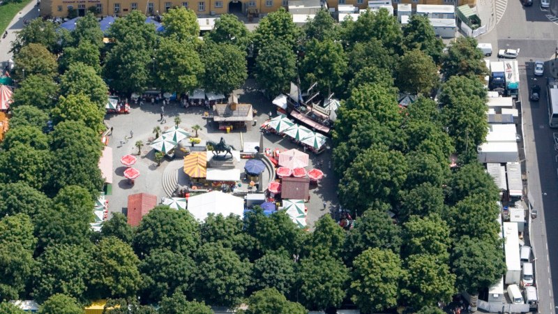 Aerial view of Karlsplatz in Stuttgart. Market stalls and colorful umbrellas are surrounded by trees. An equestrian statue stands in the center., &copy; Stuttgart-Marketing GmbH