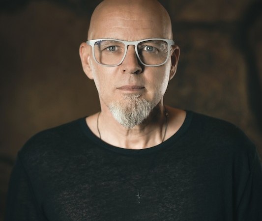 Ein Mann mit Brille und Bart blickt ernst in die Kamera. Im Hintergrund ist ein dunkler, unscharfer Hintergrund zu sehen. Unten rechts ist ein Logo des Hospitalhof Stuttgart., © TelefonSeelsorge Stuttgart e.V. Ein Mann mit Brille und Bart blickt ernst in die Kamera. Im Hintergrund ist ein dunkler, unscharfer Hintergrund zu sehen. Unten rechts ist ein Logo des Hospitalhof Stuttgart., © TelefonSeelsorge Stuttgart e.V.