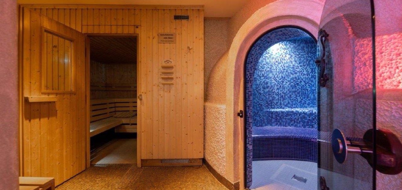 Sauna mit Holzwänden und ein angrenzendes Dampfbad mit blauen Mosaikfliesen., © Kronen Hotel GmbH Sauna mit Holzwänden und ein angrenzendes Dampfbad mit blauen Mosaikfliesen., © Kronen Hotel GmbH