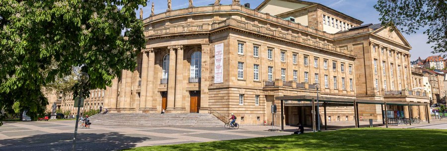 The Stuttgart State Opera in sunny weather, surrounded by green trees and a cyclist in the foreground., © Stuttgart Marketing GmbH, Sarah Schmid The Stuttgart State Opera in sunny weather, surrounded by green trees and a cyclist in the foreground., © Stuttgart Marketing GmbH, Sarah Schmid