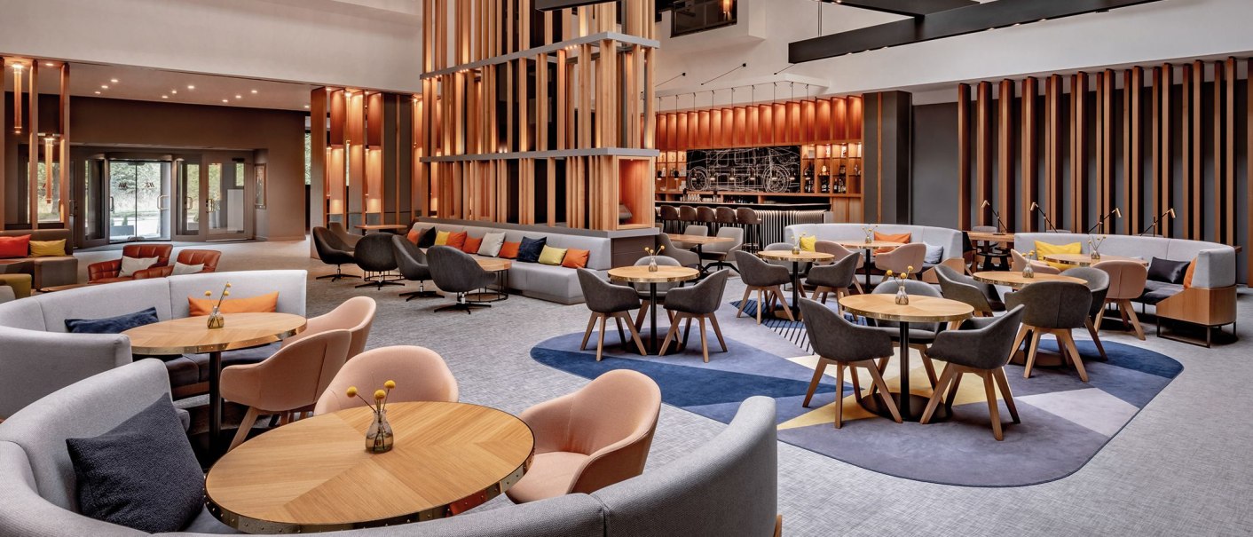 Modern lobby with elegant seating areas, wooden elements and a bar in the background. The furnishings are inviting and stylish., © Stuttgart Marriott Hotel Sindelfingen Modern lobby with elegant seating areas, wooden elements and a bar in the background. The furnishings are inviting and stylish., © Stuttgart Marriott Hotel Sindelfingen