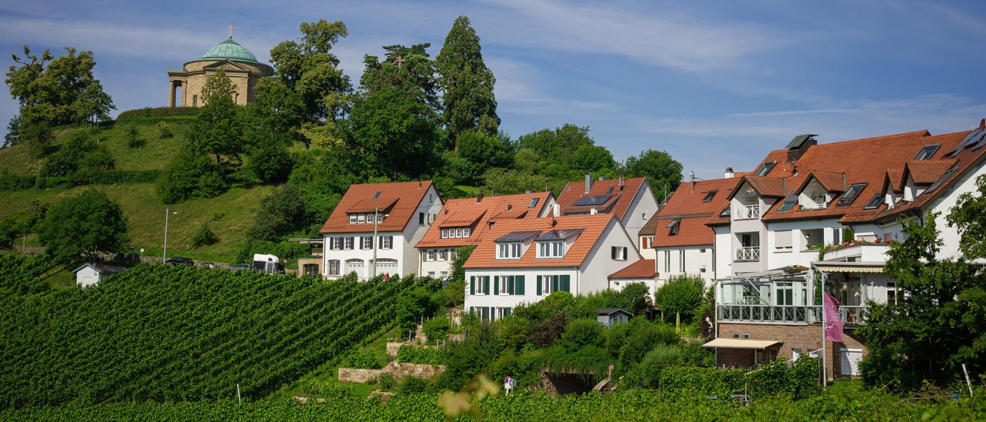 Vineyards with red roof houses, in the background a chapel on a wooded hill under a blue sky., © Rotenberger Weingärtle, Frederik Garlin Vineyards with red roof houses, in the background a chapel on a wooded hill under a blue sky., © Rotenberger Weingärtle, Frederik Garlin