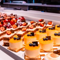 Vitrine mit verschiedenen Kuchen und Torten, darunter gelbe Törtchen mit Heidelbeeren und Erdbeerkuchen., © Sarah Schmid Vitrine mit verschiedenen Kuchen und Torten, darunter gelbe Törtchen mit Heidelbeeren und Erdbeerkuchen., © Sarah Schmid