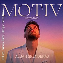 A man in a white suit looks up against a colorful background. The lettering 'MOTIV' can be seen prominently., &copy; see on the left